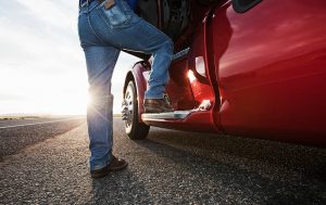 A person stepping on the side of a red truck.