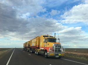 A yellow truck is driving down the road